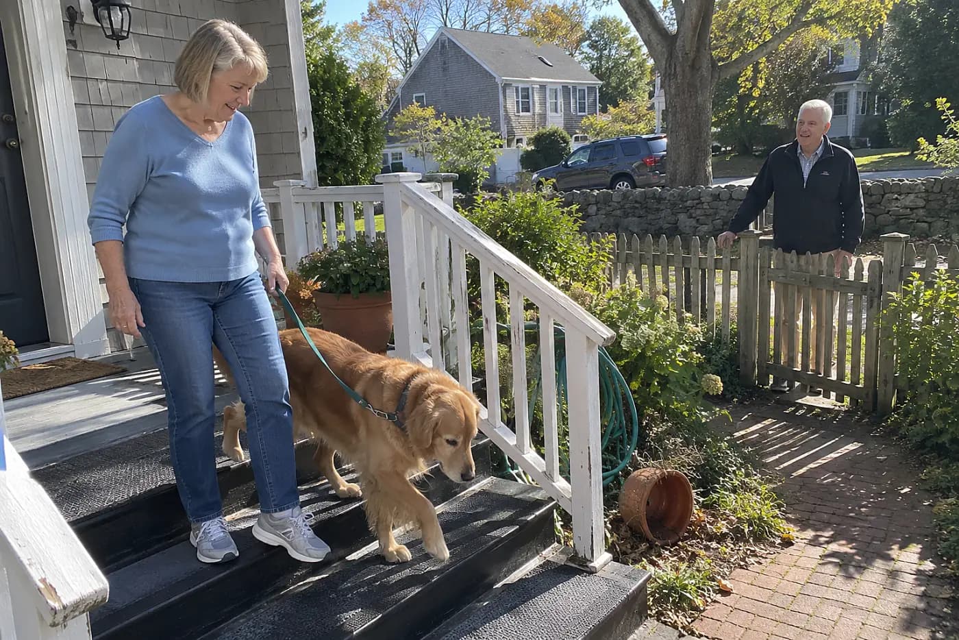 An older woman stands beside her dog as he tests a grippy porch step.