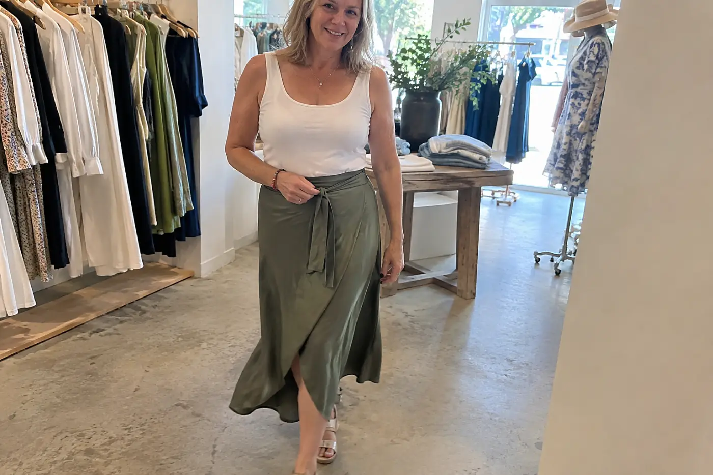 Older woman trying a wrap midi skirt with her own shoes in a clothing store.