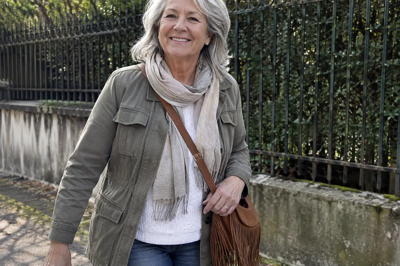 Older woman walking down a street with a fringed crossbody bag.