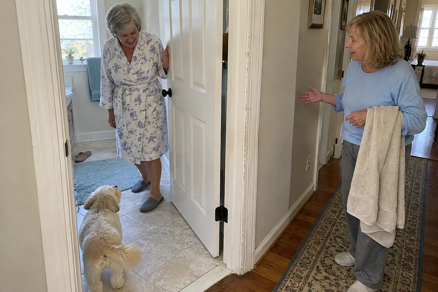 Older woman opening a bathroom door while her dog waits on the tile floor.