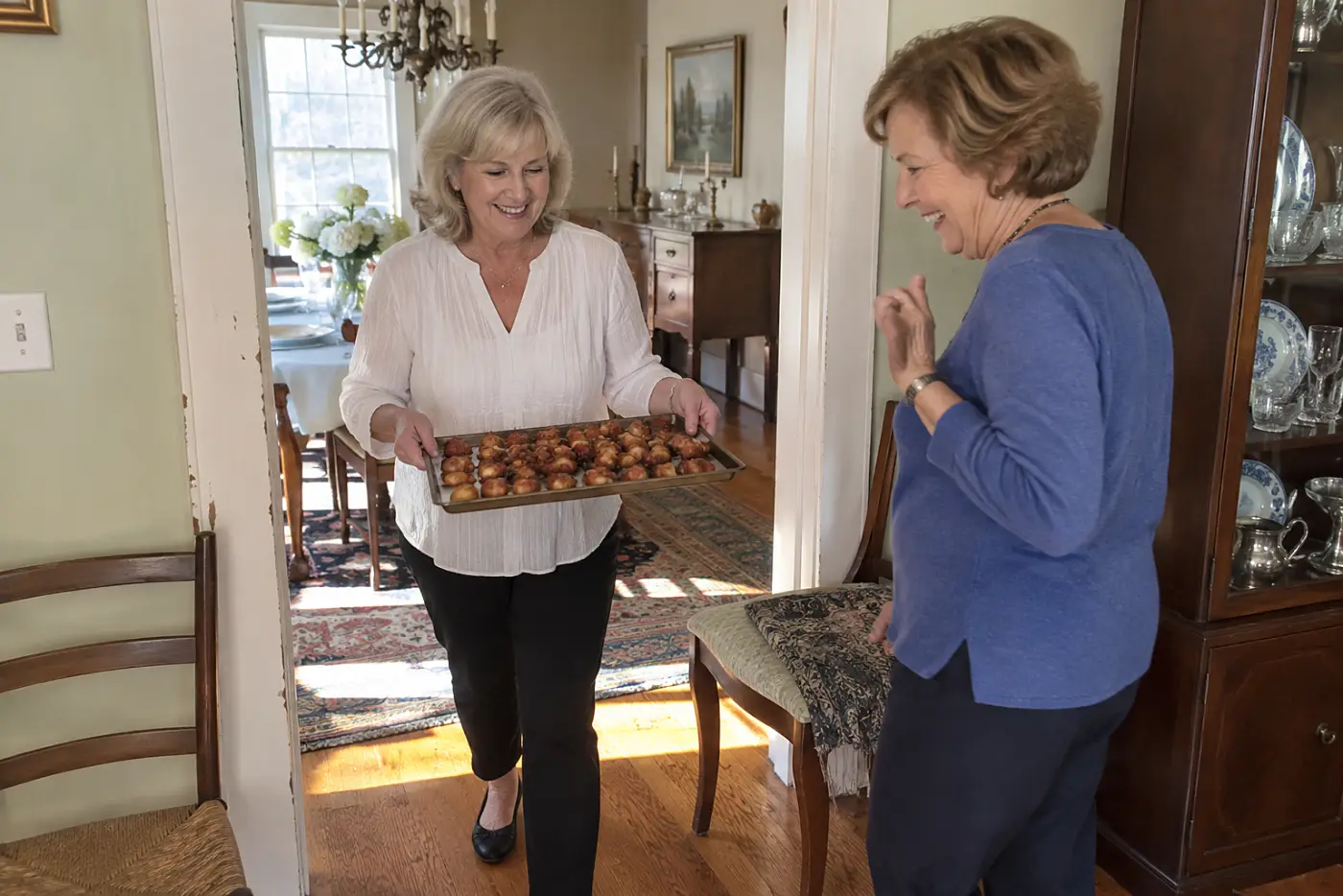 A woman carries a tray of bacon-wrapped water chestnuts through a dining-room doorway.