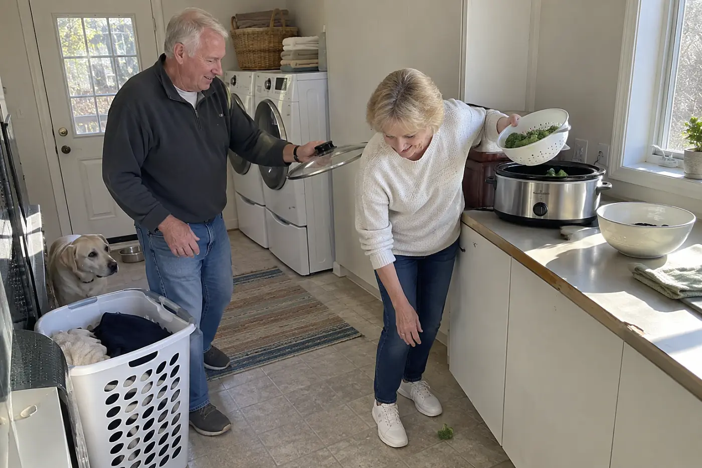 A man adds broccoli to a slow cooker in a small apartment kitchenette.