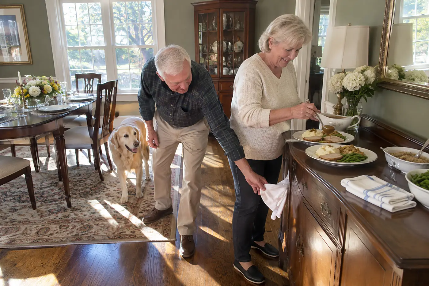 Woman spoons gravy onto two warm dinner plates in a dining room.