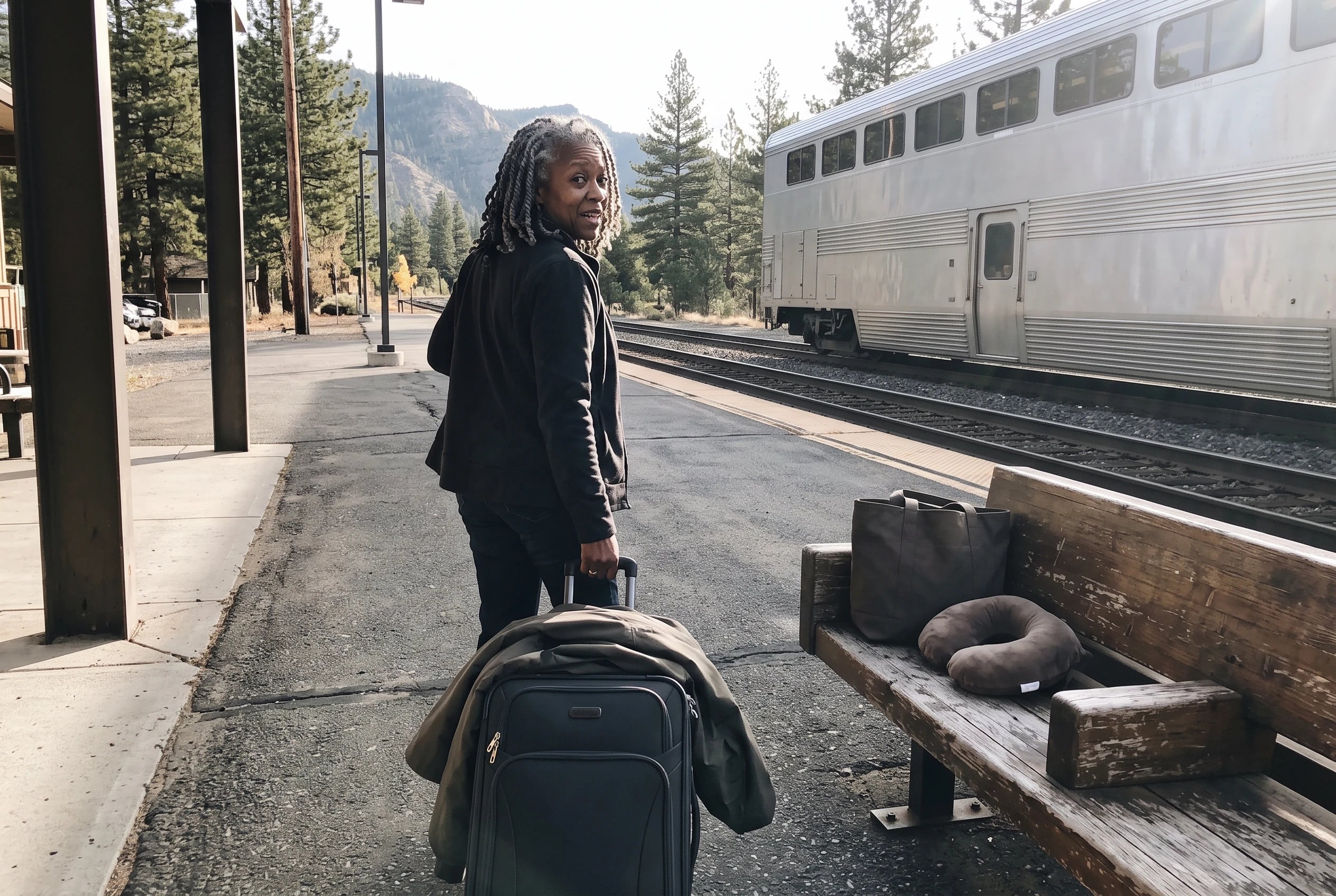 An older woman rolls her suitcase along the West Glacier station platform beside the Empire Builder.