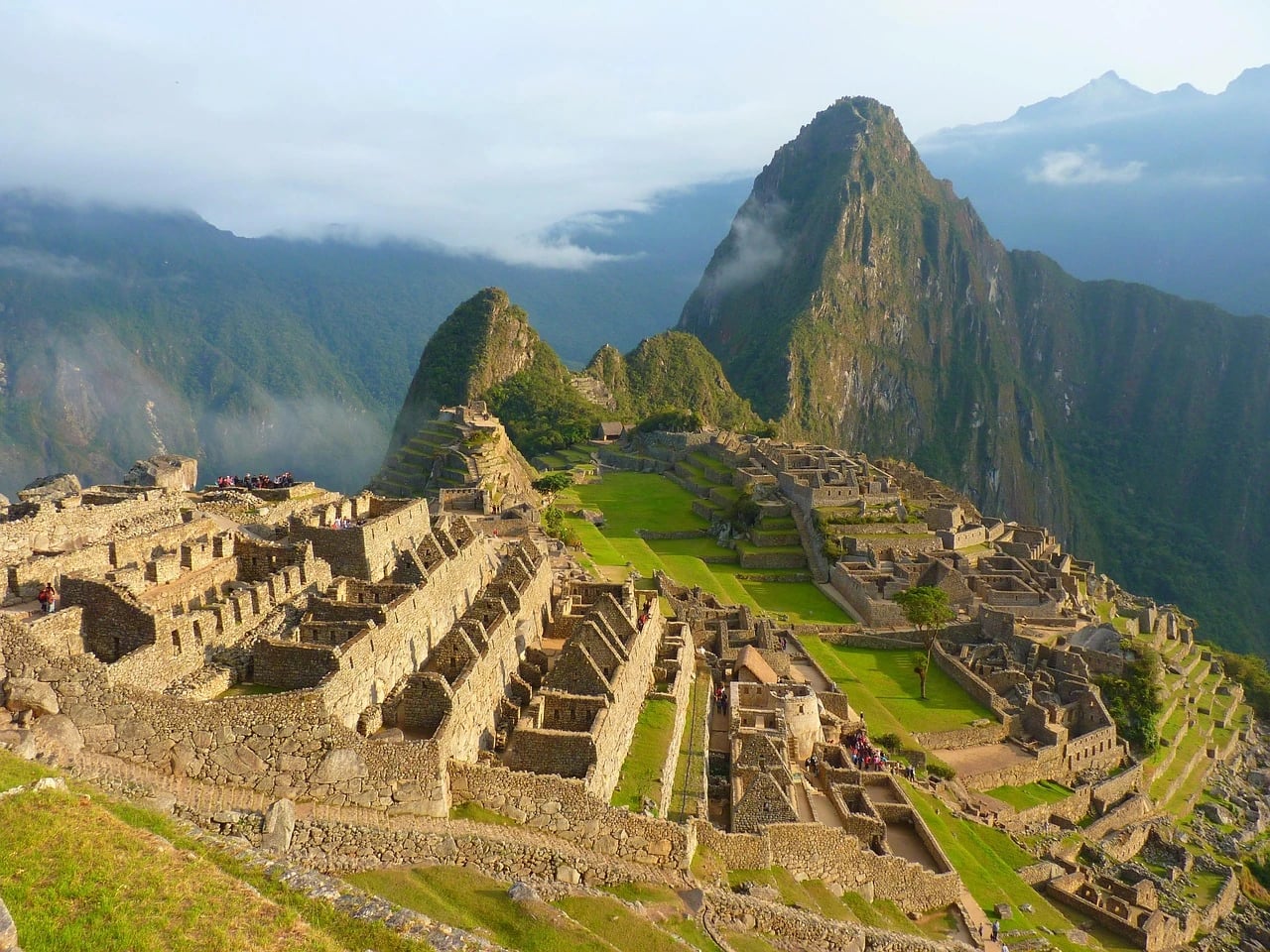 Aerial view of Machu Picchu's stone ruins and green terraces beneath Huayna Picchu peak in the Andes