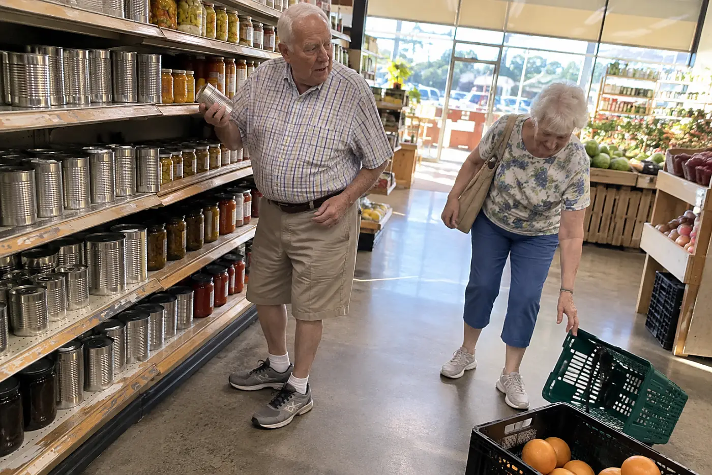 A man selects canned beans from a grocery store shelf.