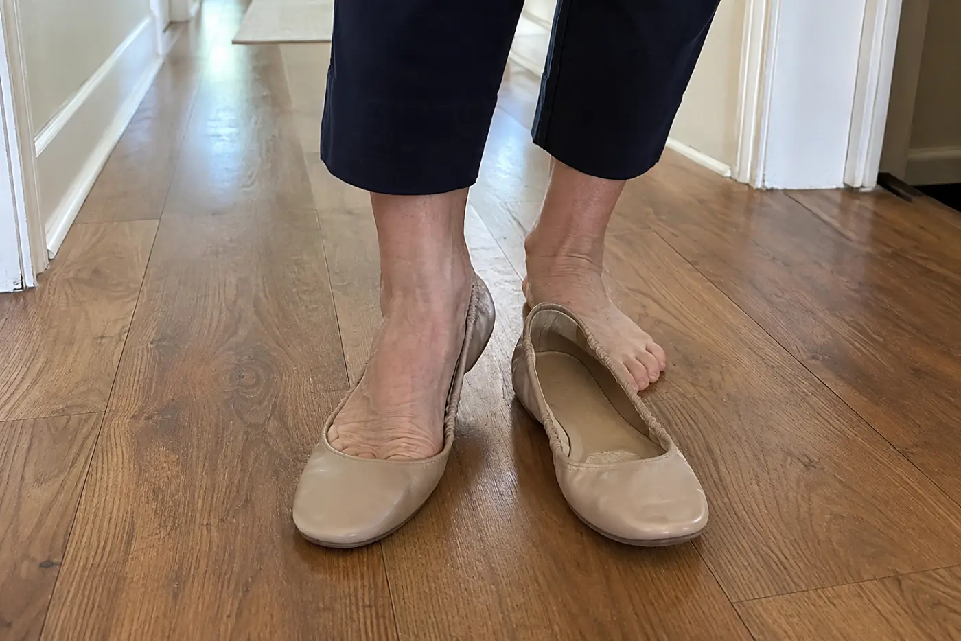 A woman in her sixties steps into beige ballet flats with elastic heels.