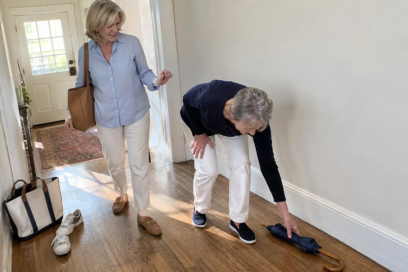 A woman in her sixties wears a powder blue Oxford shirt in a hallway.