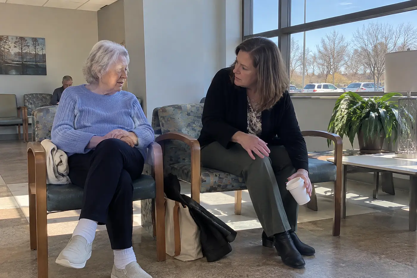 Older woman talking with her health care agent in a hospital waiting room.