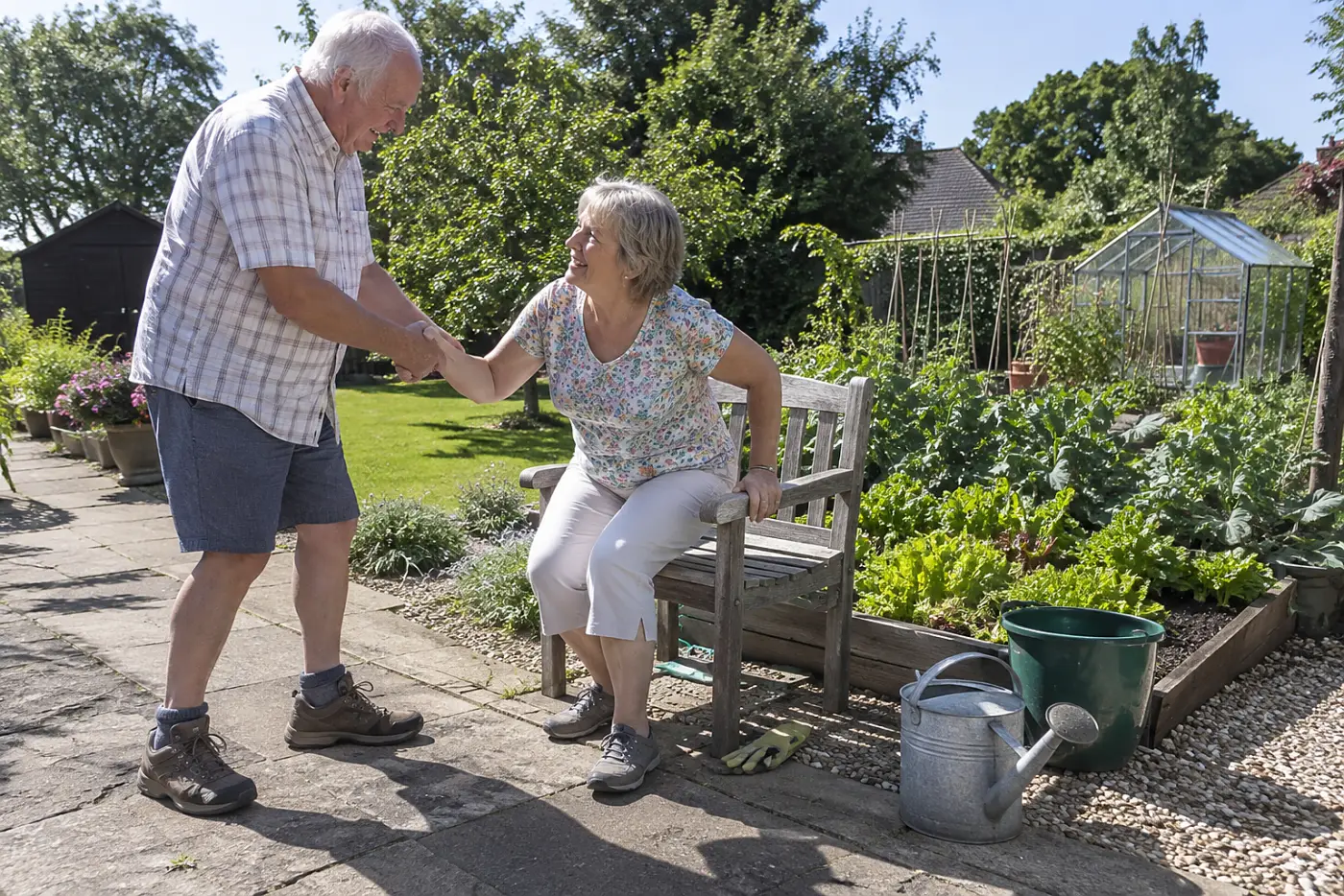 Older woman standing up from a garden seat beside a vegetable bed.