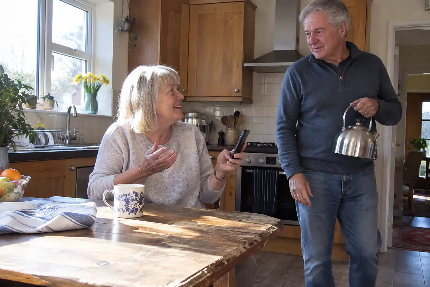 Older woman ending a phone call at her kitchen table.