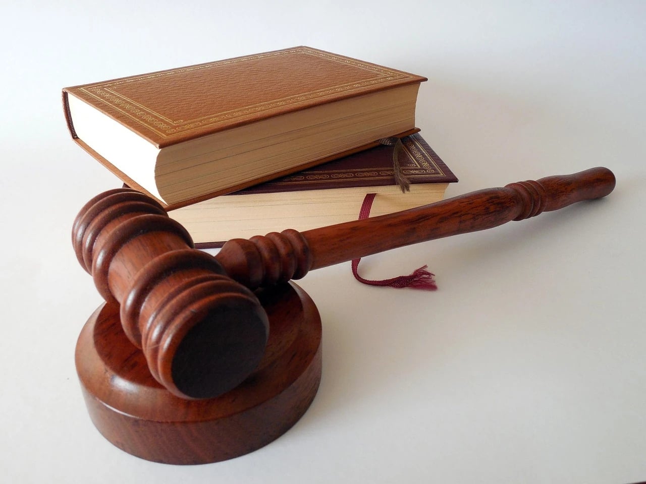 Wooden gavel resting on its block in front of two stacked leather-bound law books