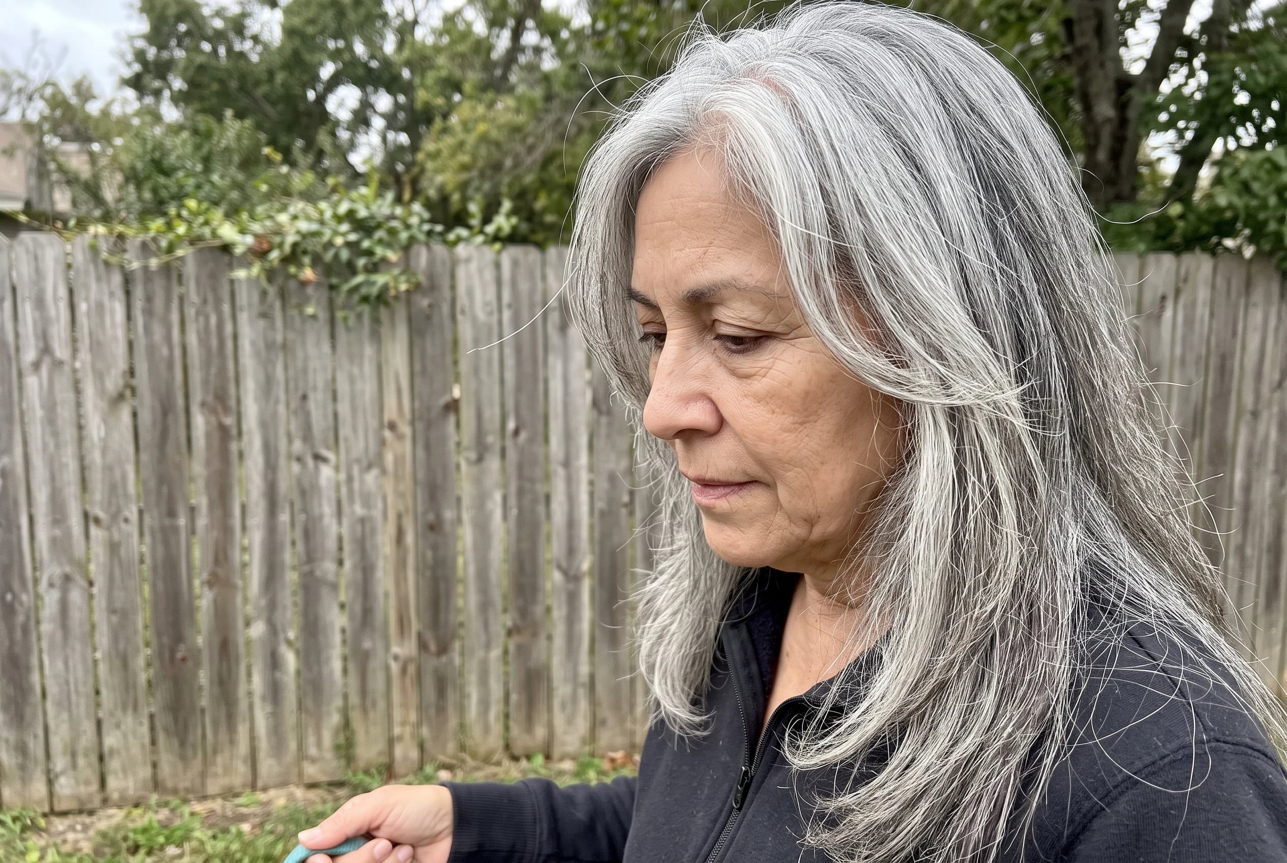 A long cut with face-framing pieces falls past the shoulders of a woman in her sixties walking her dog.