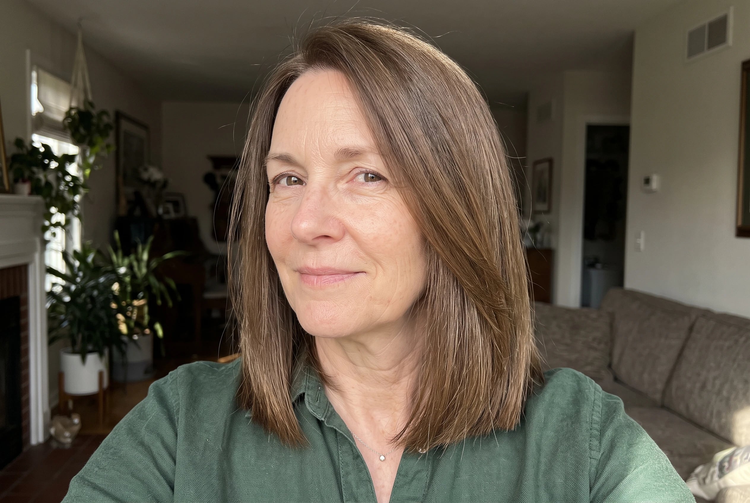 A blunt-ended lob with interior layers swings as a woman in her sixties turns toward a bedroom mirror.