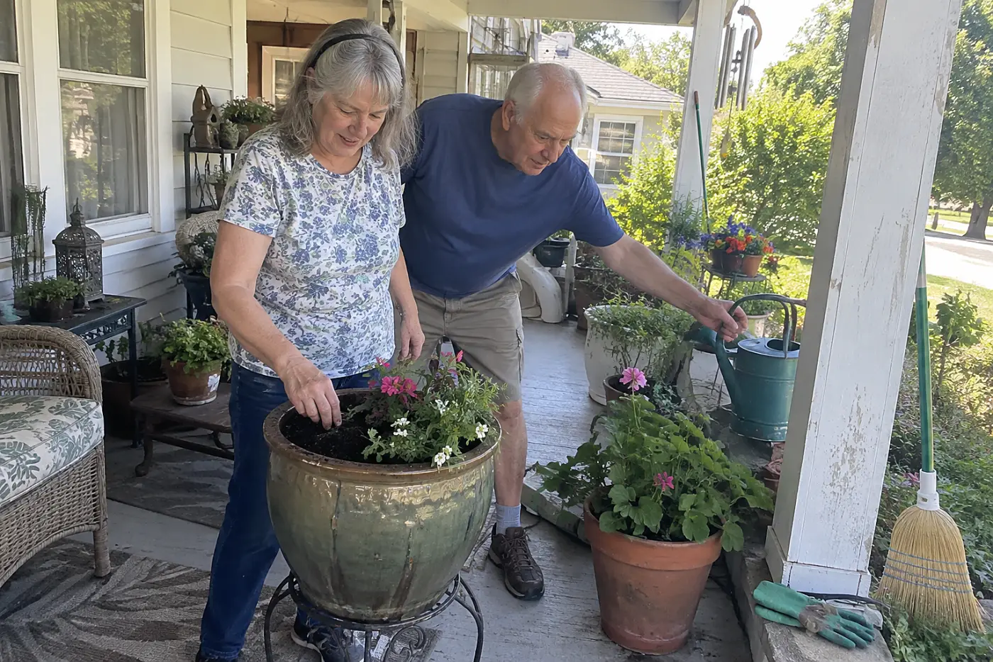 Older woman pressing a finger into the soil of a porch planter.