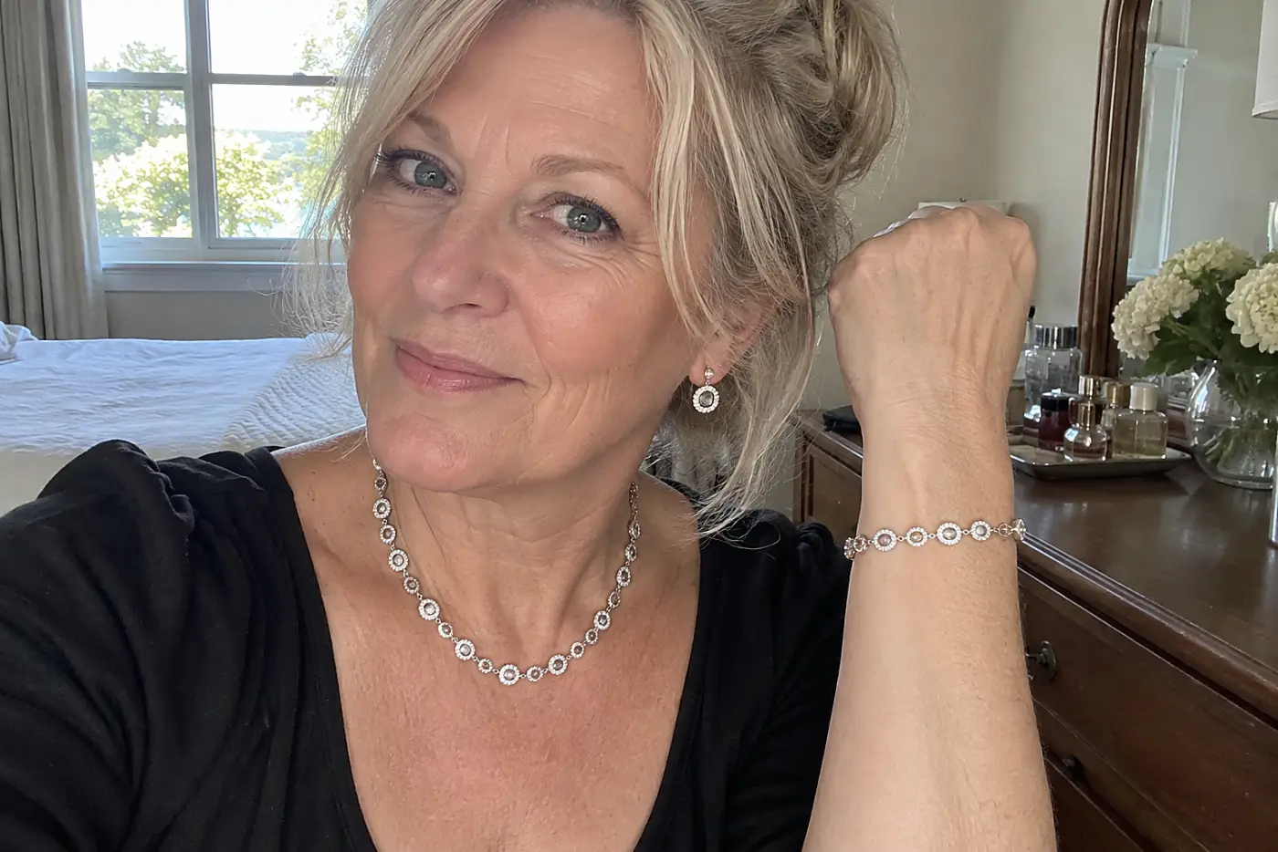 A woman in her sixties wearing a matching silver necklace, earring, and bracelet set.