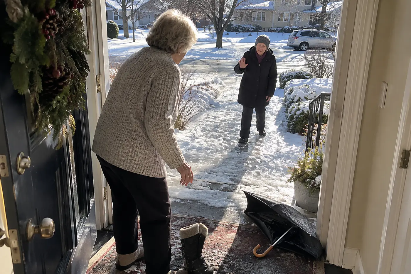 Older woman looking at ice on the front steps from her doorway.