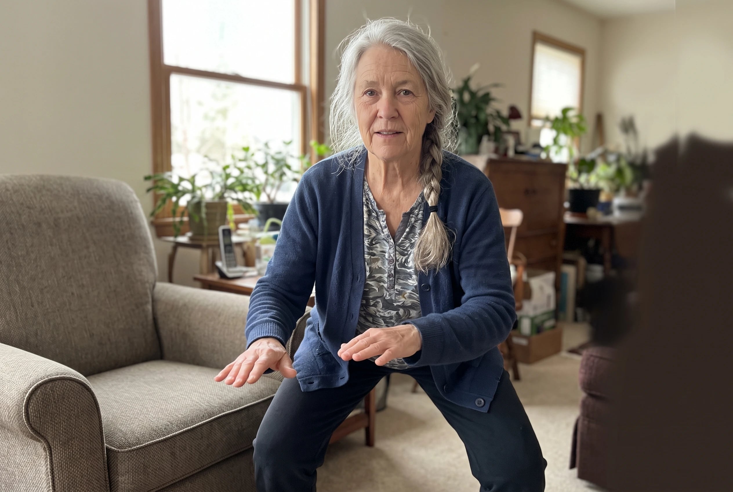Woman bending her knees slightly in a wide stance beside a chair in her den.
