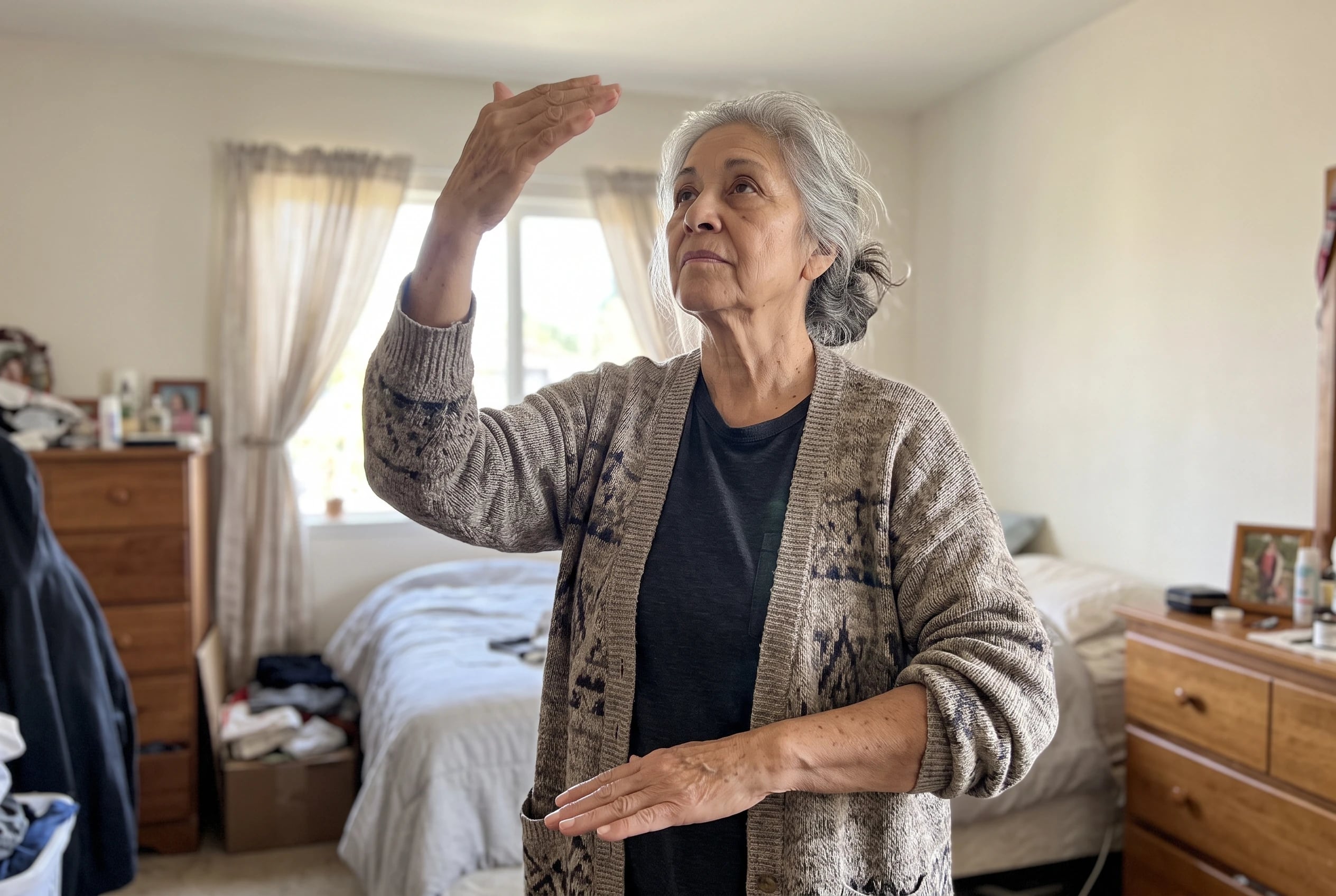 Woman pressing one palm upward and the other downward in a bedroom.