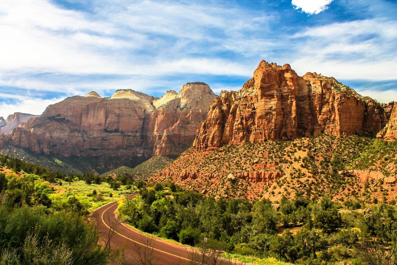 Red sandstone cliffs and a winding park road through green trees in Zion National Park