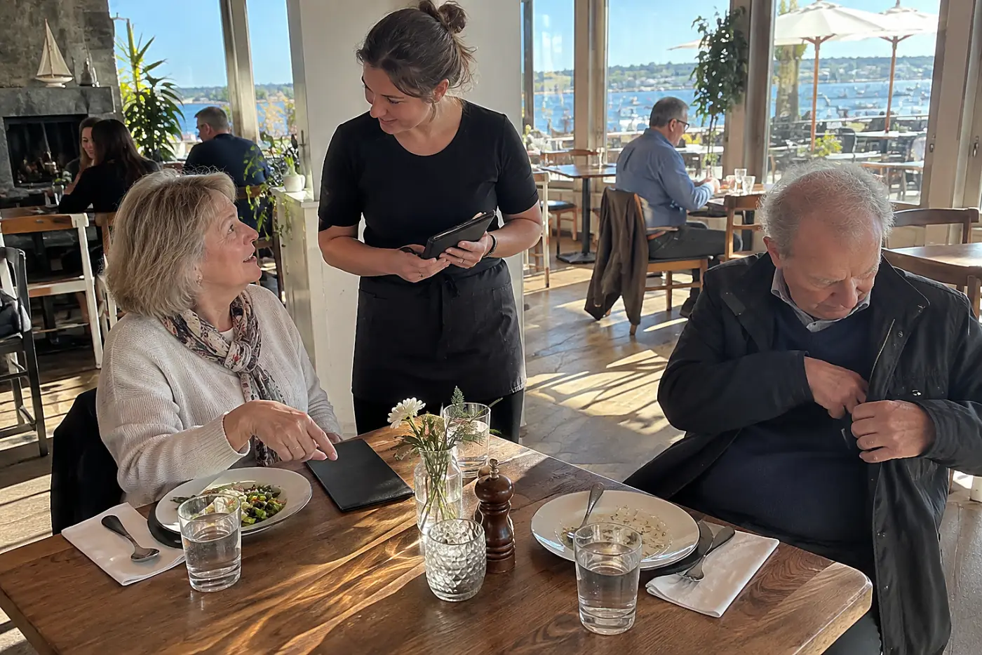 Older woman speaking to a server about the check at lunch.