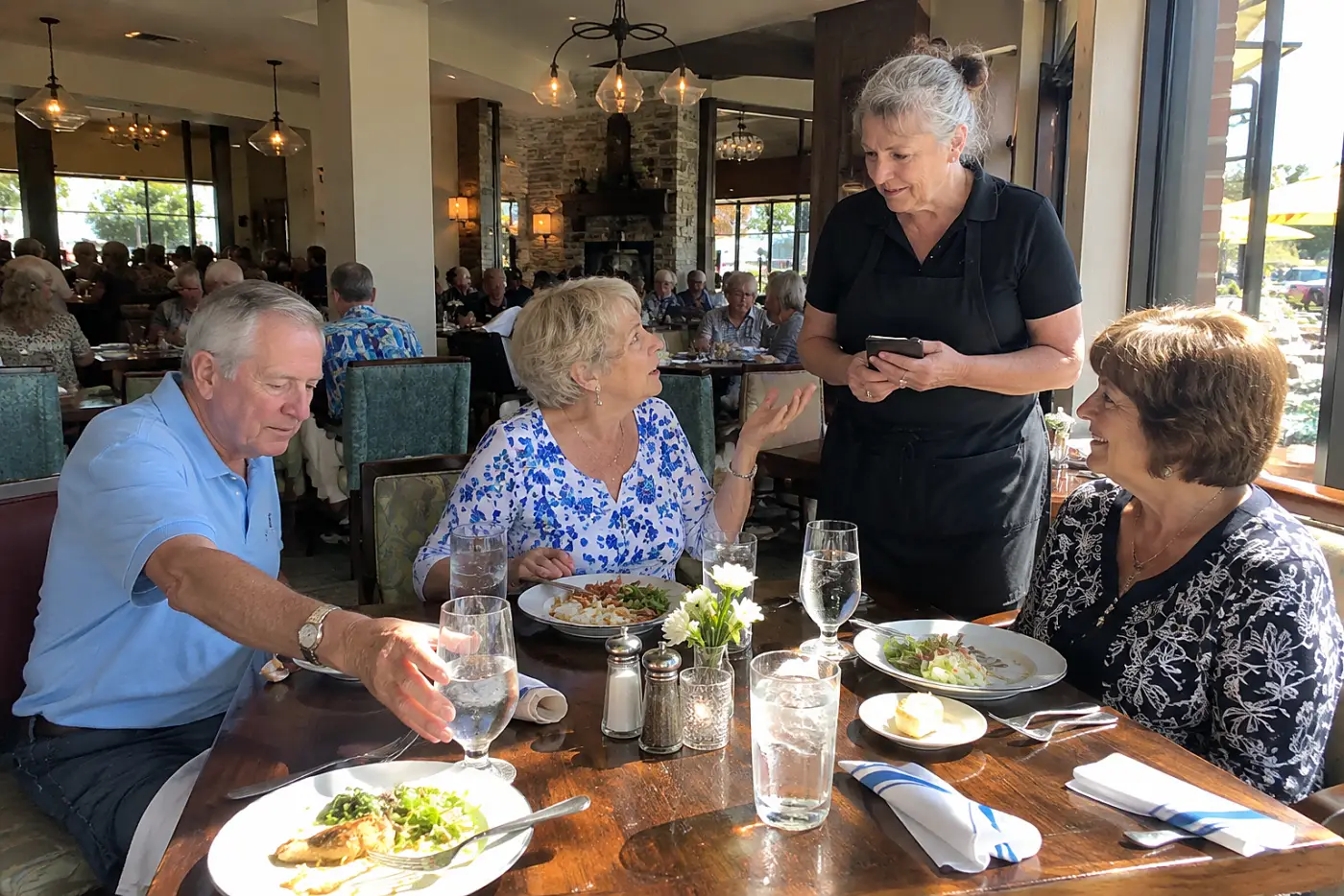 Older woman asking a server for separate checks at a restaurant table.