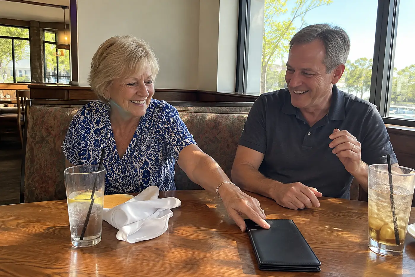 Older woman reaching for a restaurant bill across from her son.