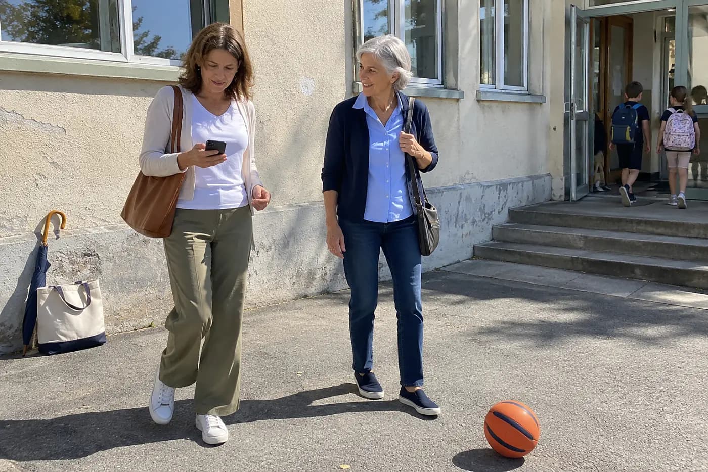Adult daughter looking at her ringing phone while waiting outside a school.