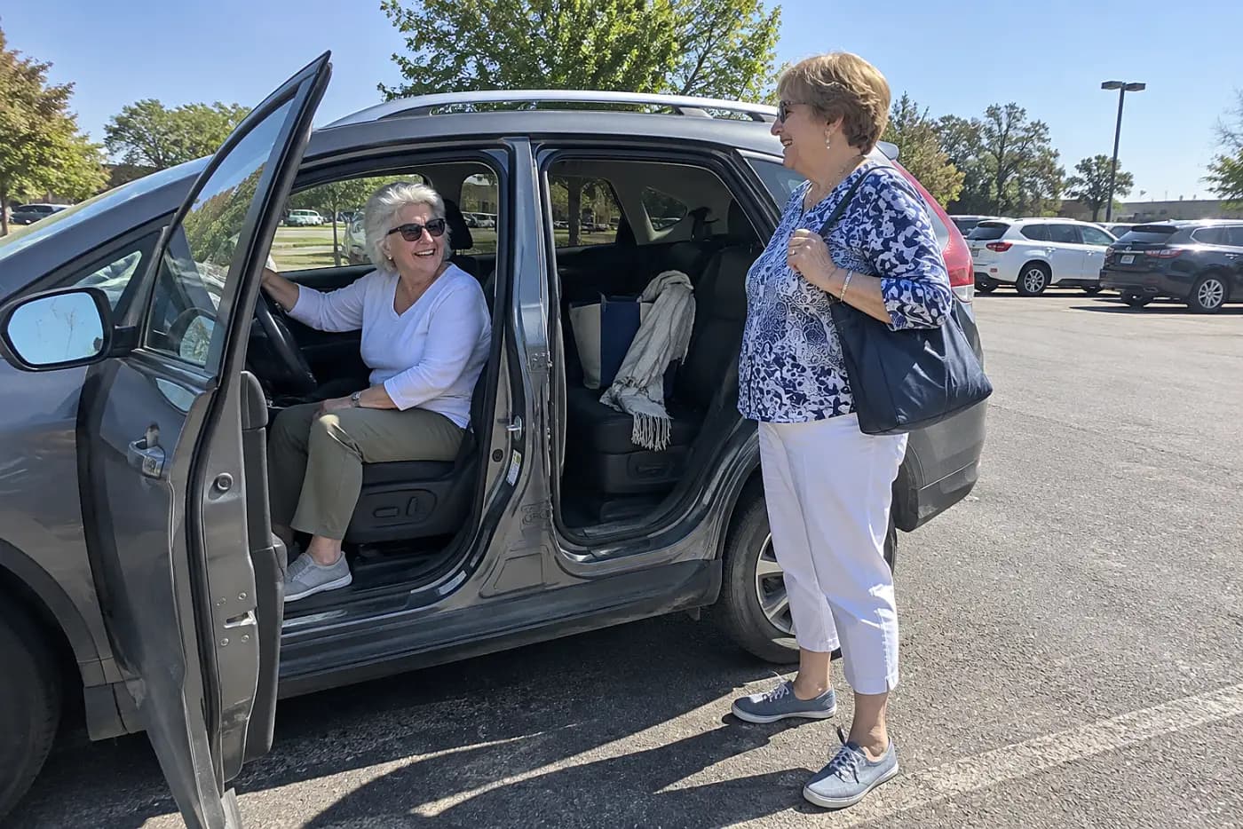 Older woman turns in the driver's seat before stepping out of a parked car.
