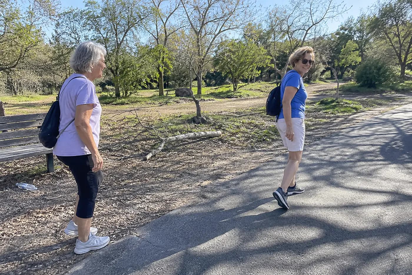 Older woman pauses at a gravel path in a neighborhood park.