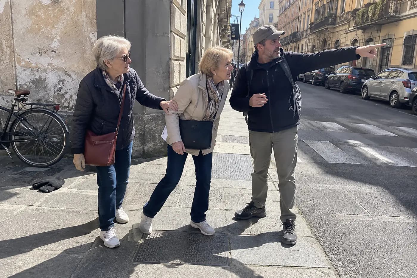 Older woman listening to a guide on a city sidewalk.