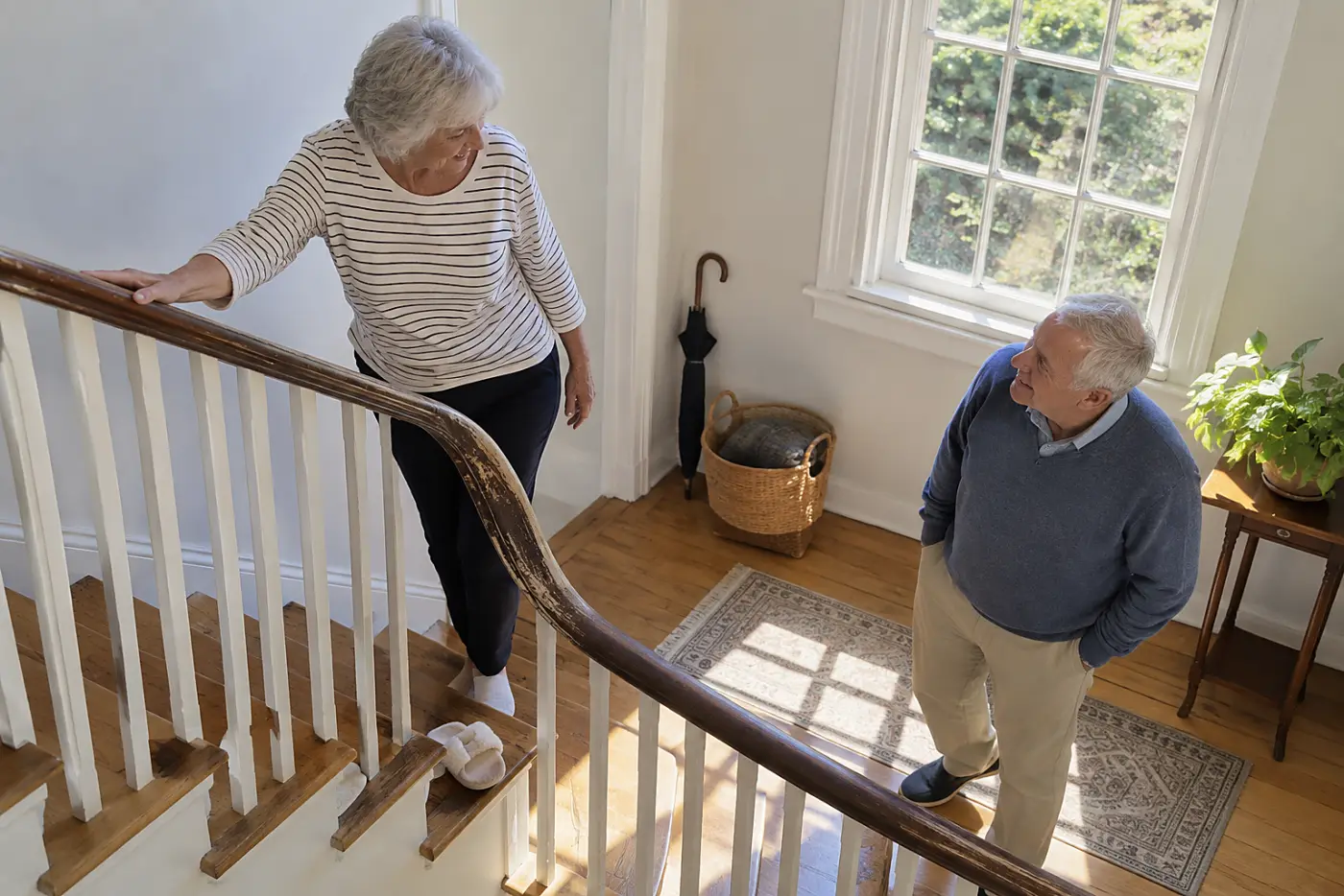 Older woman resting a hand on the rail at a stair landing.