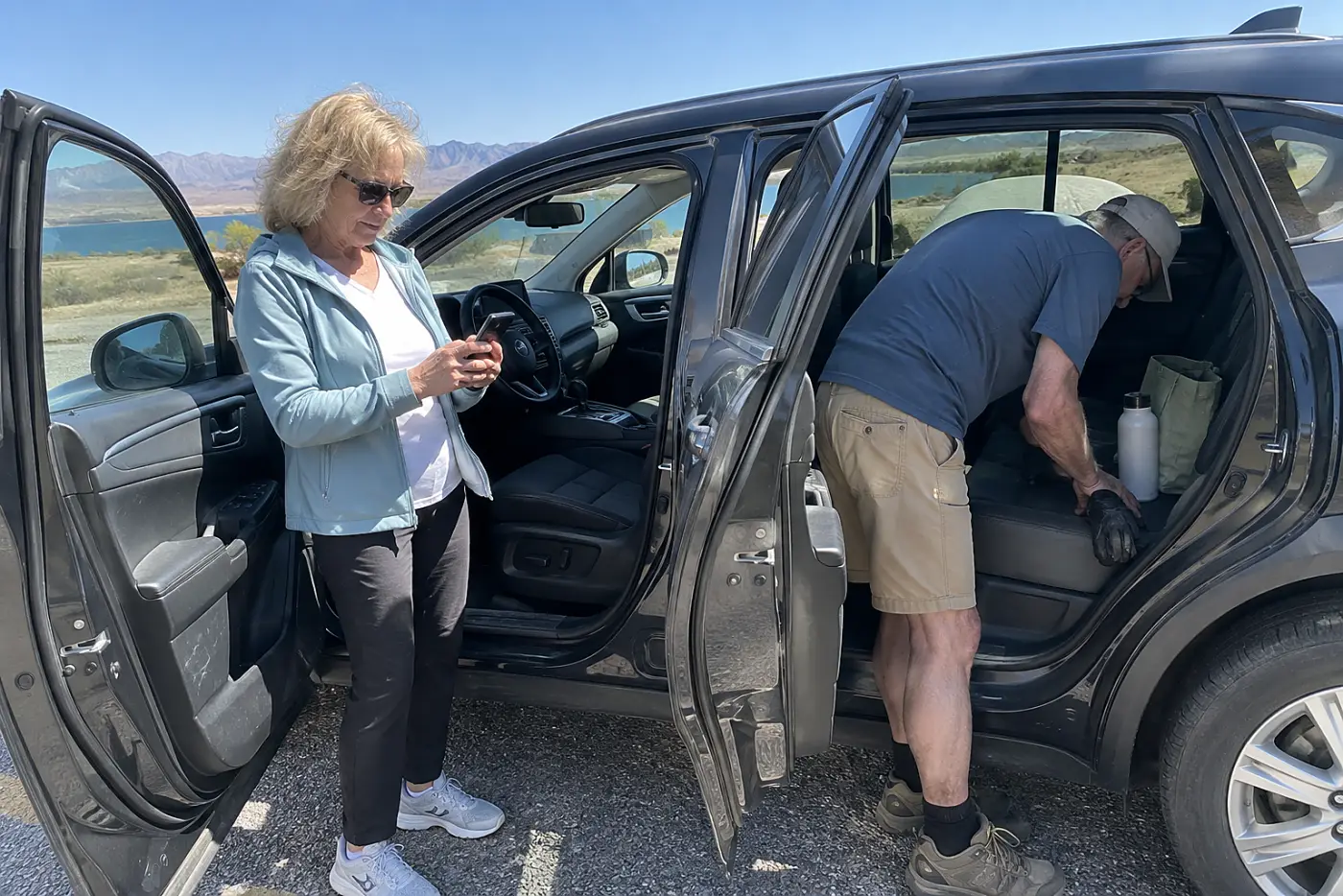 Older woman checking her vehicle account on a phone in her parked car.