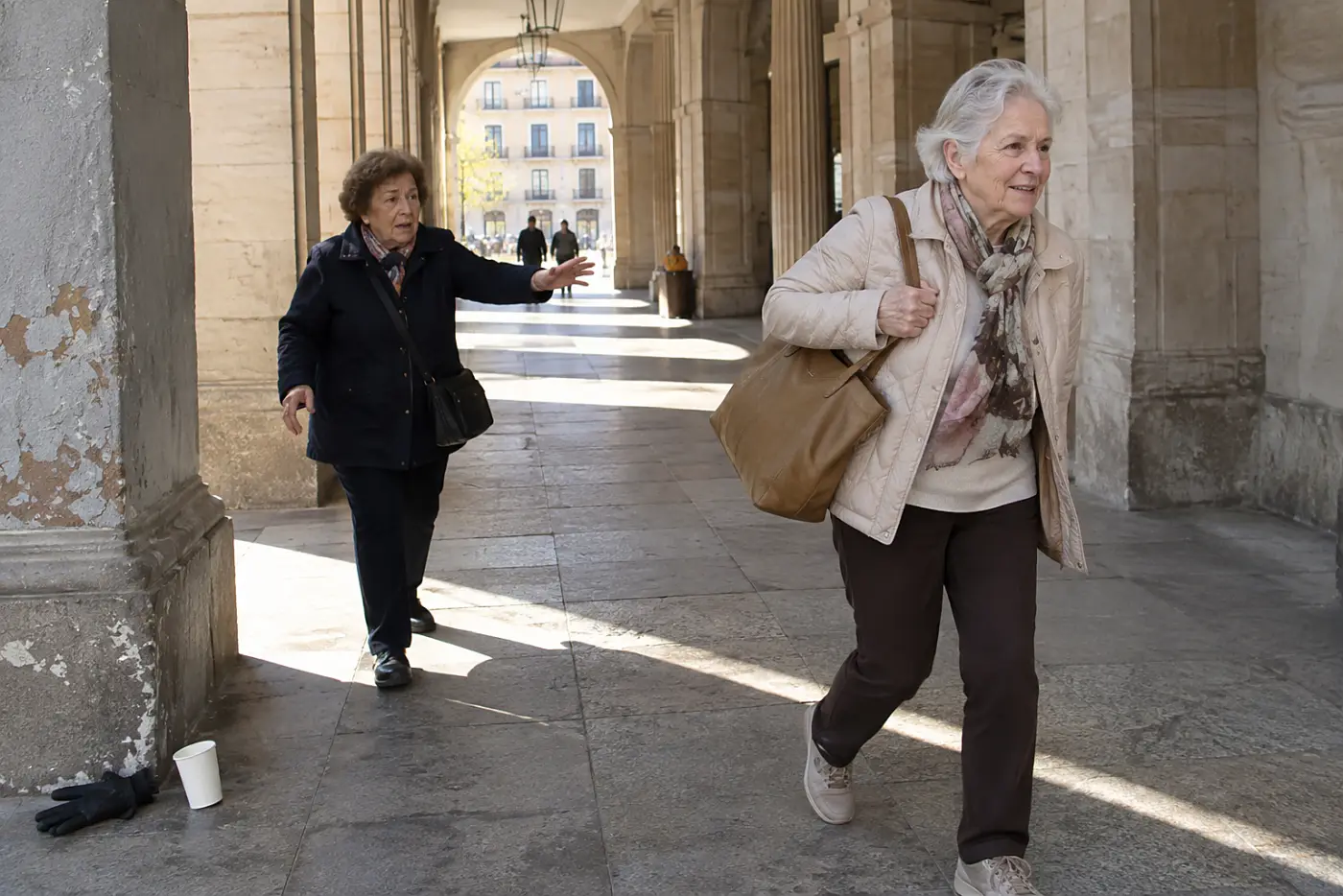 Woman walking beneath a covered arcade between city blocks.