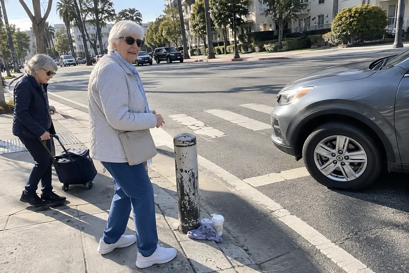 Woman watching turning cars from a sidewalk beside a left-turn lane.