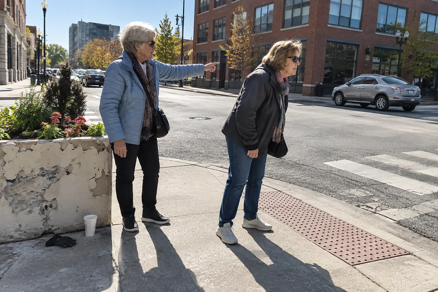 Woman looking across a street toward the opposite curb ramp.