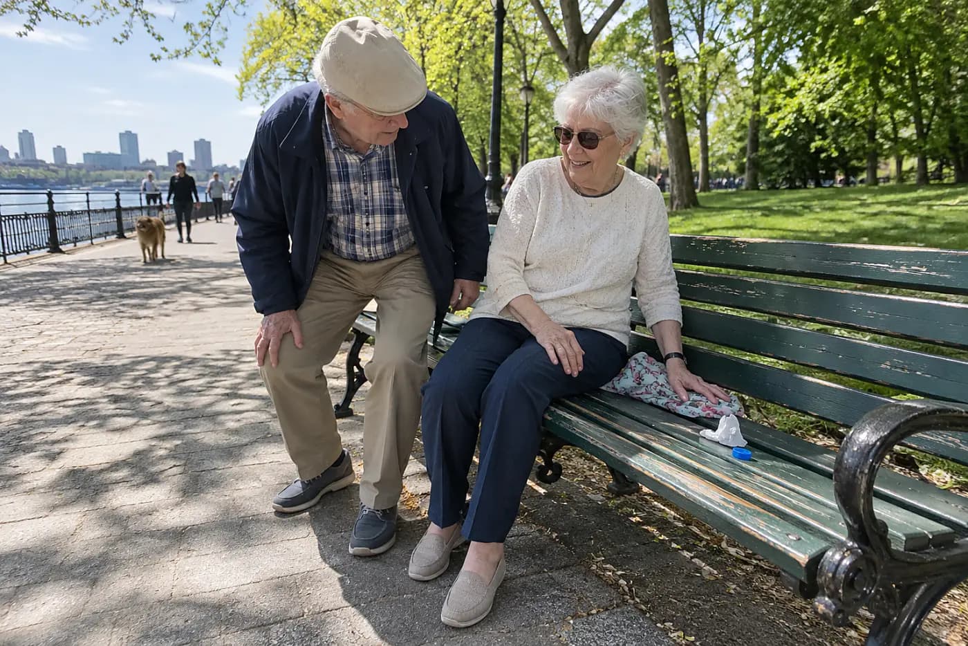 Older woman sitting on a park bench beside a city footpath.