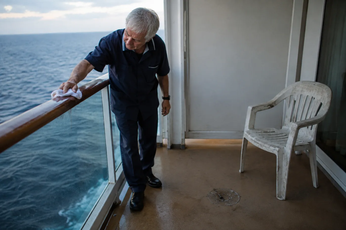 Steward wipes a balcony railing, noticing an ash smudge on the deck.
