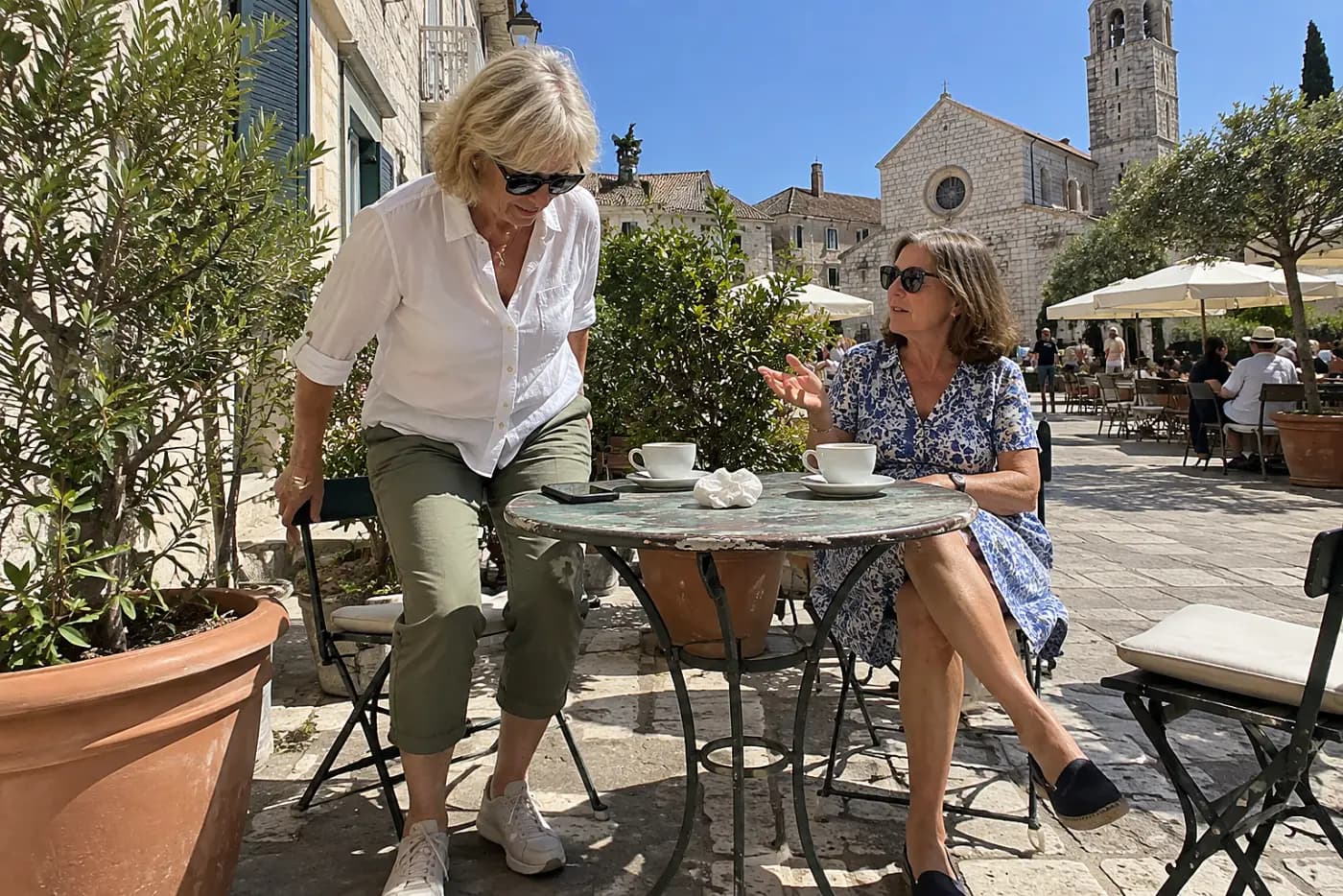 Older woman checking museum hours on her phone at a cafe table.