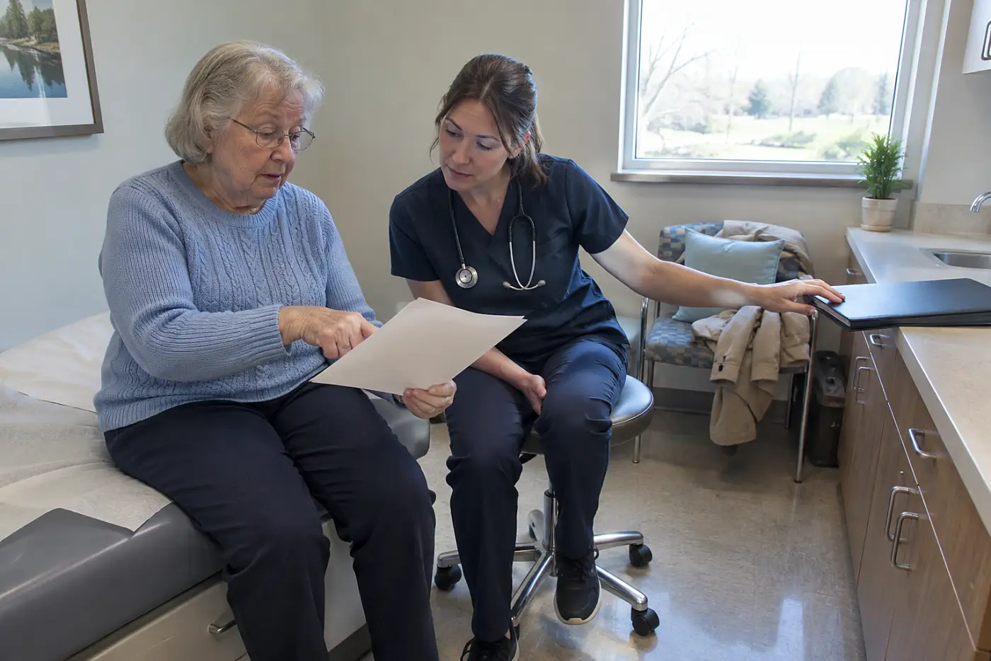 Older woman pointing to an empty space on her visit summary while speaking with a nurse.