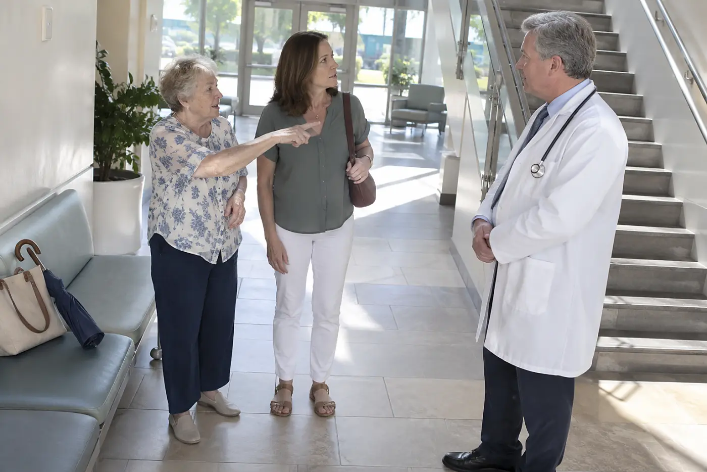 Older woman pointing toward a staircase while speaking with a doctor at a clinic.