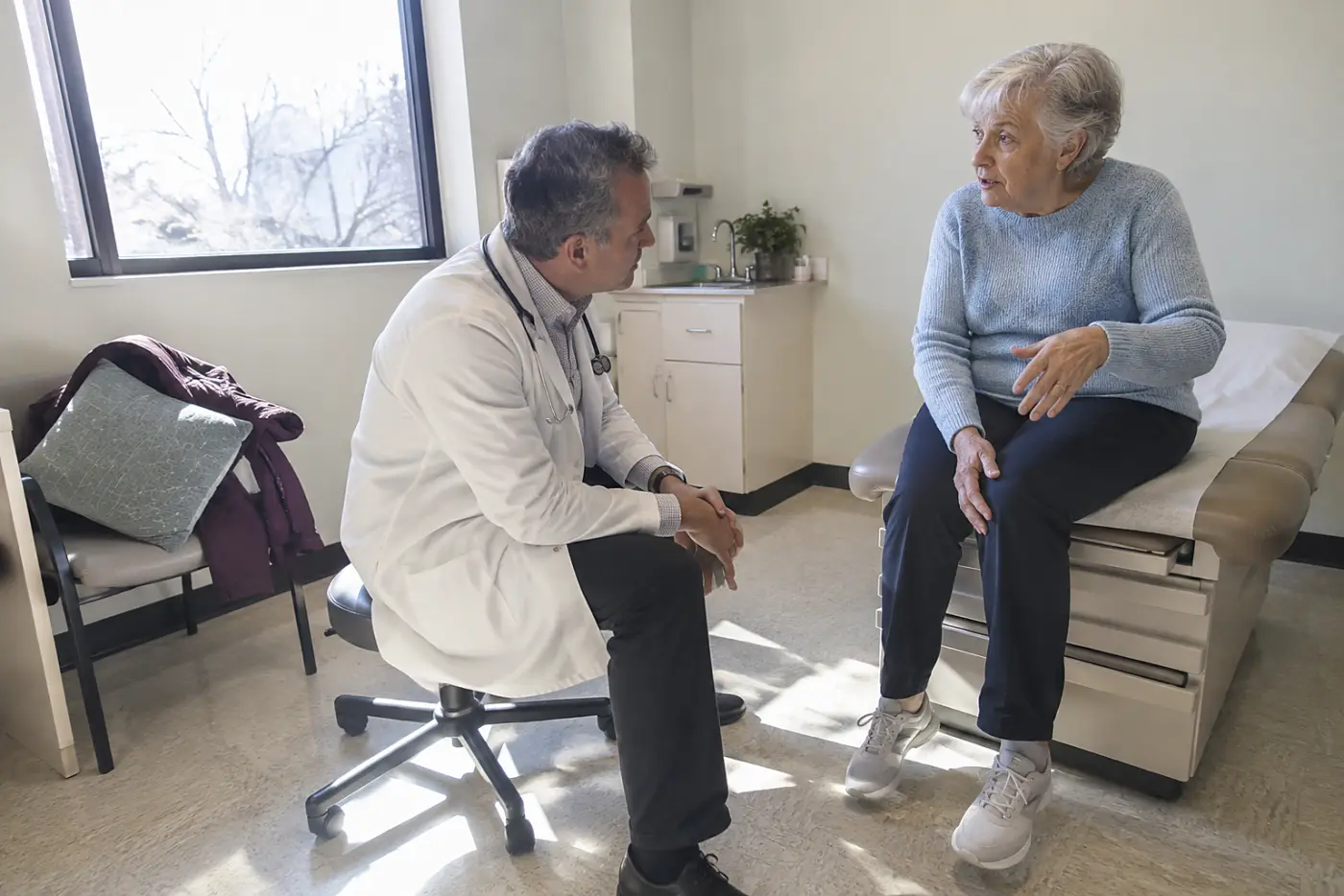 Older woman describing a locked knee to a doctor in an exam room.