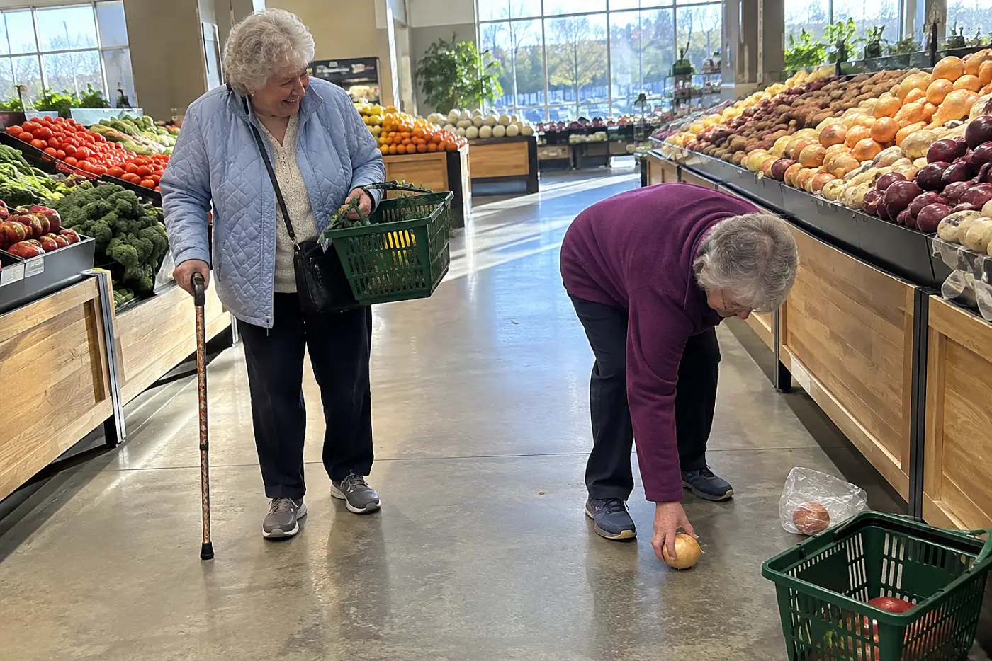 Older woman walking down a grocery store aisle with a cane.