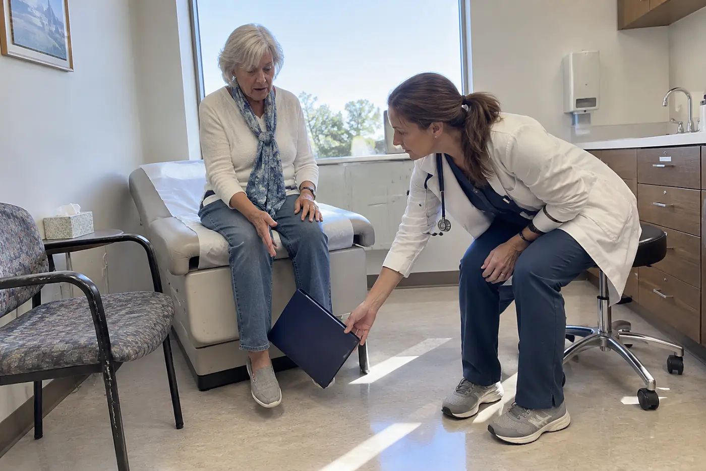 Older woman reviewing treatment options with a clinician in an exam room.