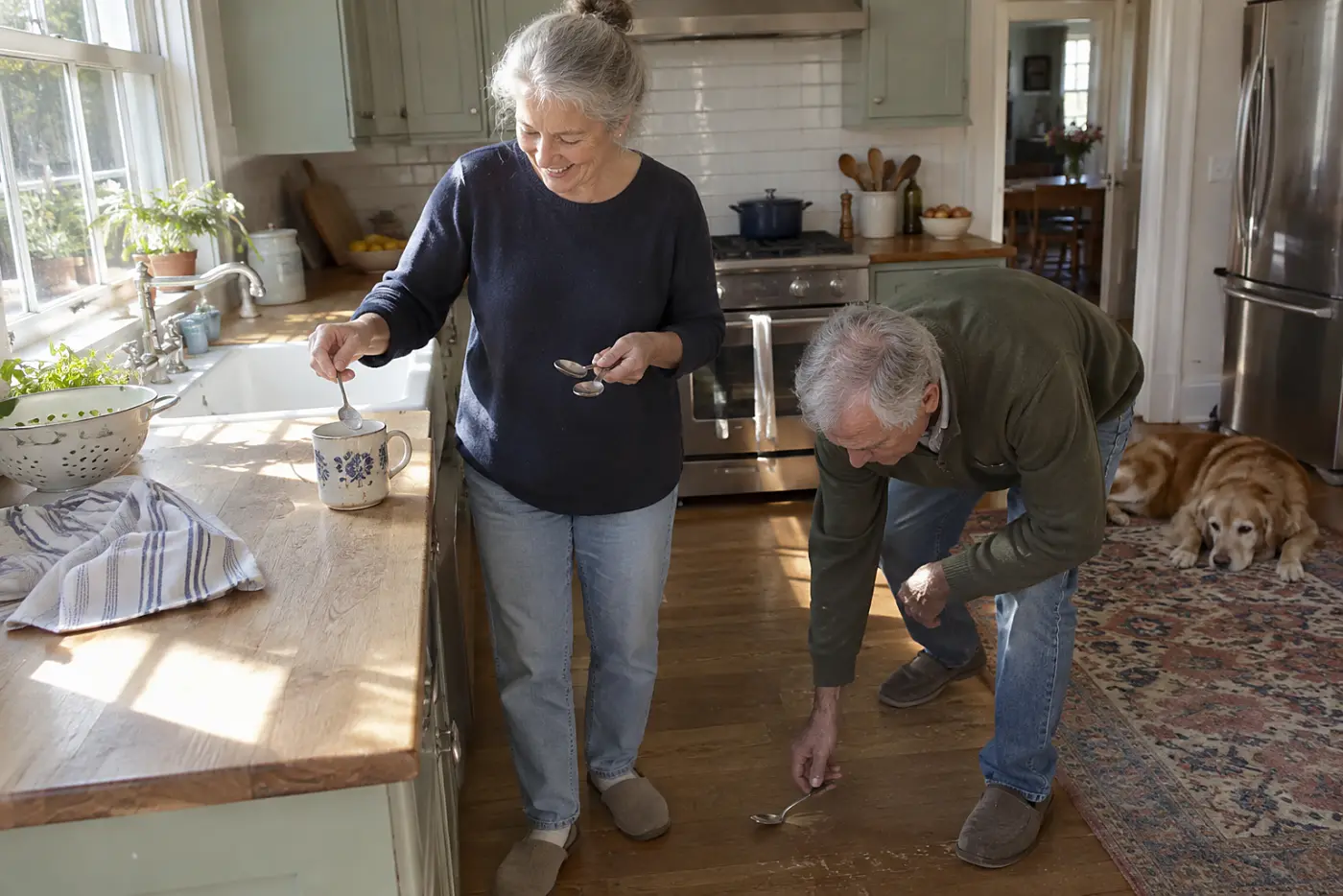 Older woman placing teaspoons in a chipped mug on her kitchen counter.