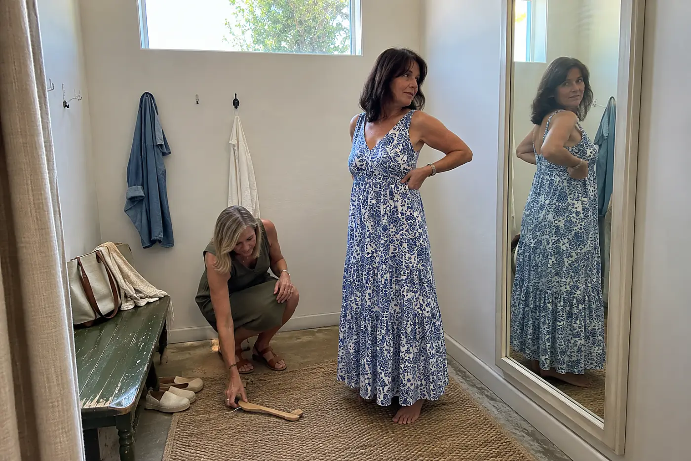 Older woman checking a dress seam in a fitting-room mirror.