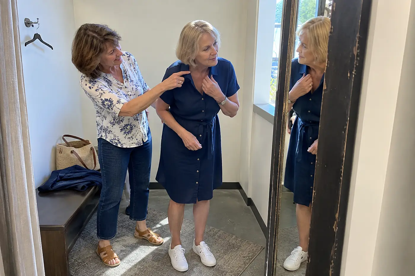 Older woman bending forward to check a neckline in a fitting-room mirror.