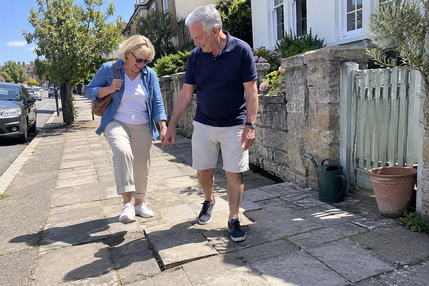 Older couple walking together on a sidewalk near their home.