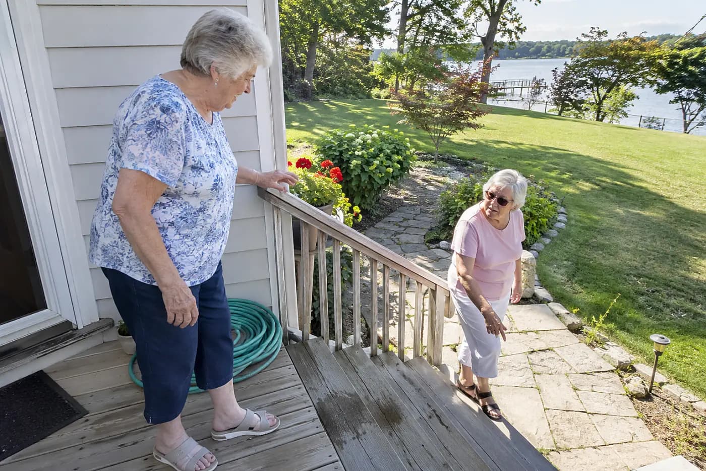 Older woman reaching for a handrail before descending outdoor stairs.