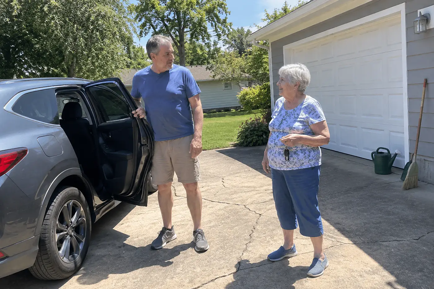 Older woman holding car keys while talking with her son in a driveway.